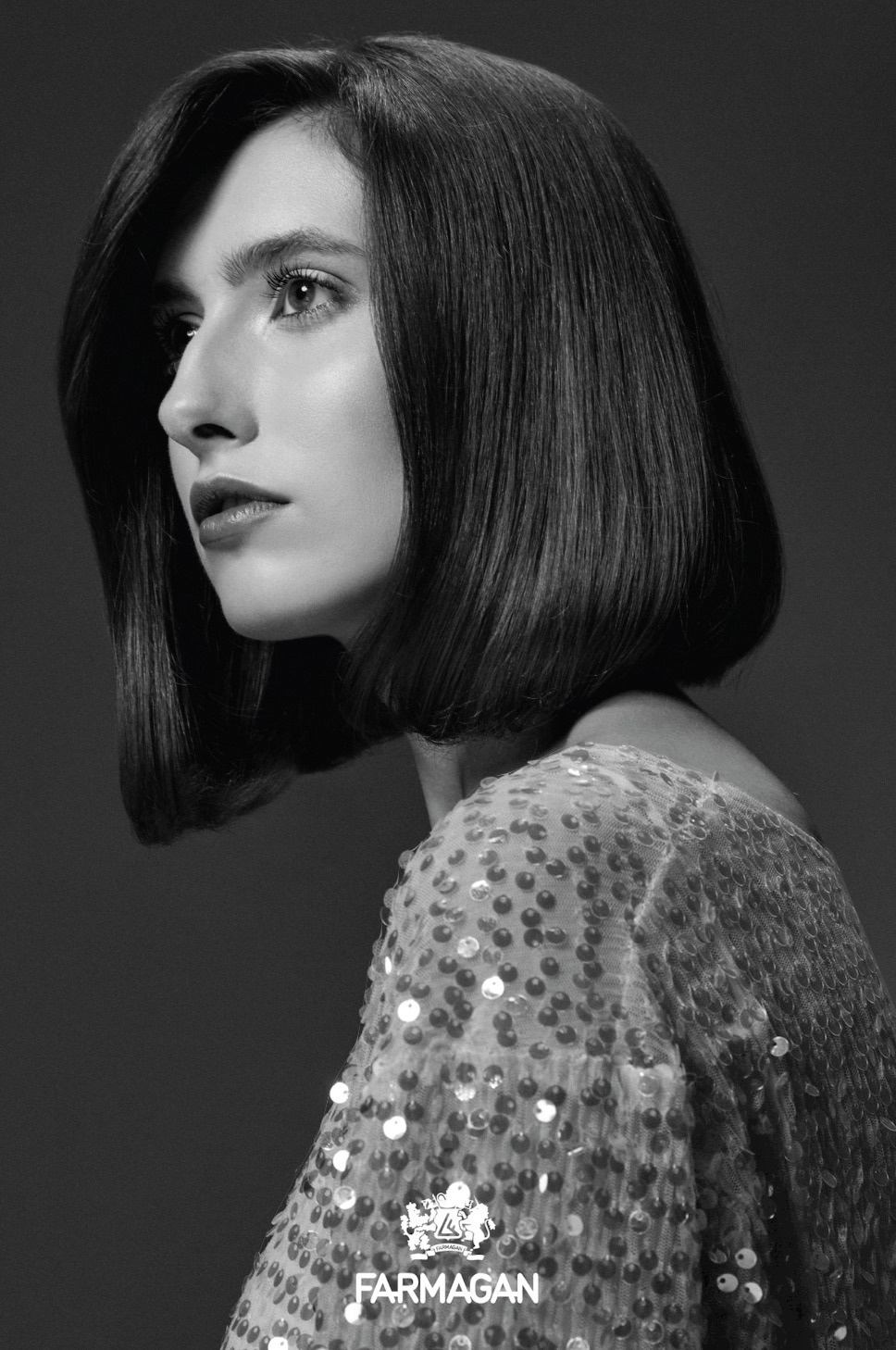 Portret kobiety z ciemnymi, gładkimi włosami do ramion, w sukience pokrytej cekinami, profil, czarno-białe zdjęcie z logo Farmagan.