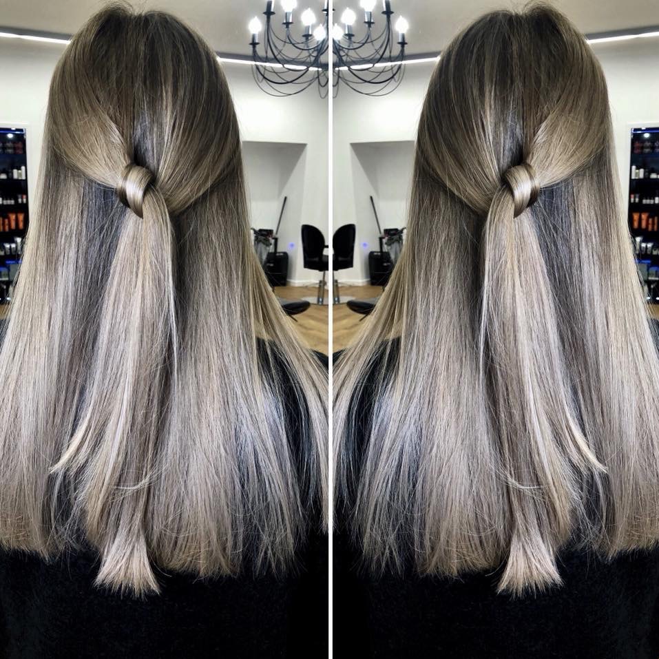 Włosy w odcieniach blondu z delikatnym upięciem z tyłu głowy, wykonane w salonie w Lublinie, widok z tyłu na tle wnętrza salonu.