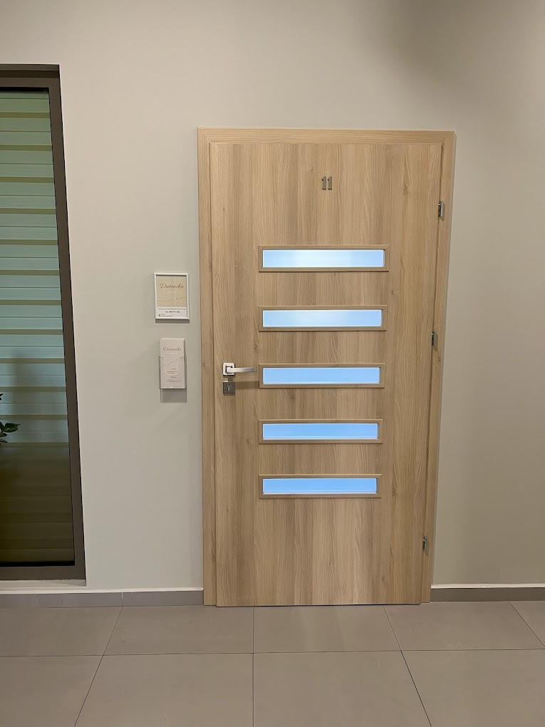 Drzwi do gabinetu numer 11 w Raciborzu, z wizytówkami na ścianie, sugerujące usługi z zakresu zdrowia.