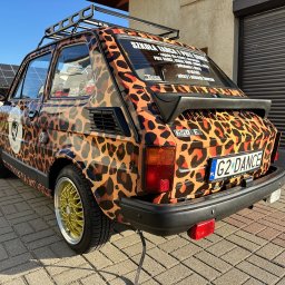K. B. Sp. z o.o. - Samochód Fiat 126p oklejony folią w panterkę z napisem 'Szkoła Tańca i Pole Dance' na tylnej szybie, na złotych felgach, z bagażnikiem dachowym