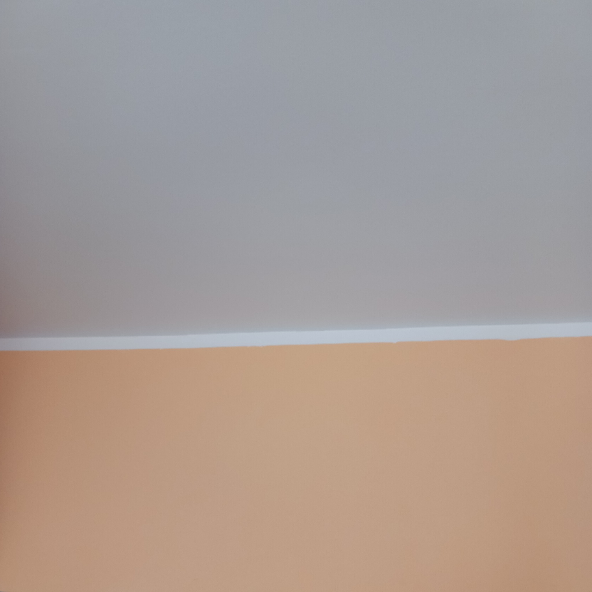 Ściana pomalowana na kolor brzoskwiniowy z białym pasem oddzielającym ją od szarego sufitu.