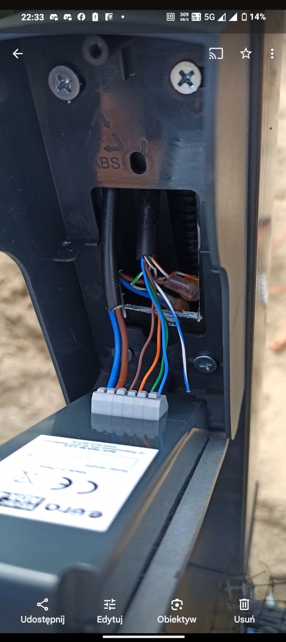 Szczegółowe ujęcie podłączenia przewodów elektrycznych o różnych kolorach do listwy zaciskowej wewnątrz czarnej obudowy urządzenia, widoczne śruby mocujące i oznaczenie ABS na obudowie.