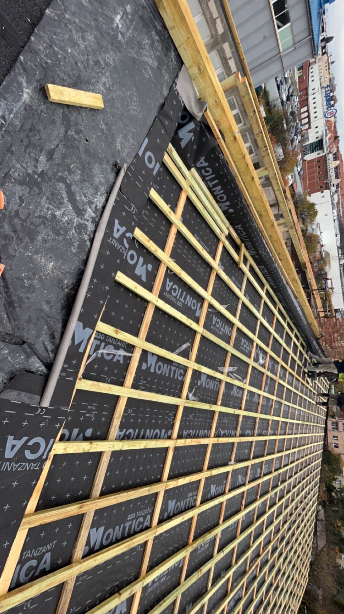 Konstrukcja drewniana dachu z membraną hydroizolacyjną MONTICA, widoczna w trakcie budowy w Tczewie, z budynkami w tle.