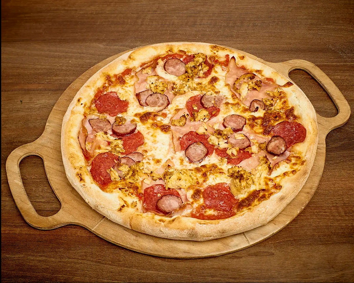 Pizza z salami, kiełbasą, szynką i kurczakiem na drewnianej desce do serwowania.