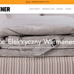 Jakub Majewski - Szary koc elektryczny Warmener złożony na pufie w paski, z widocznym panelem sterowania i przewodami, na tle jasnej sofy.