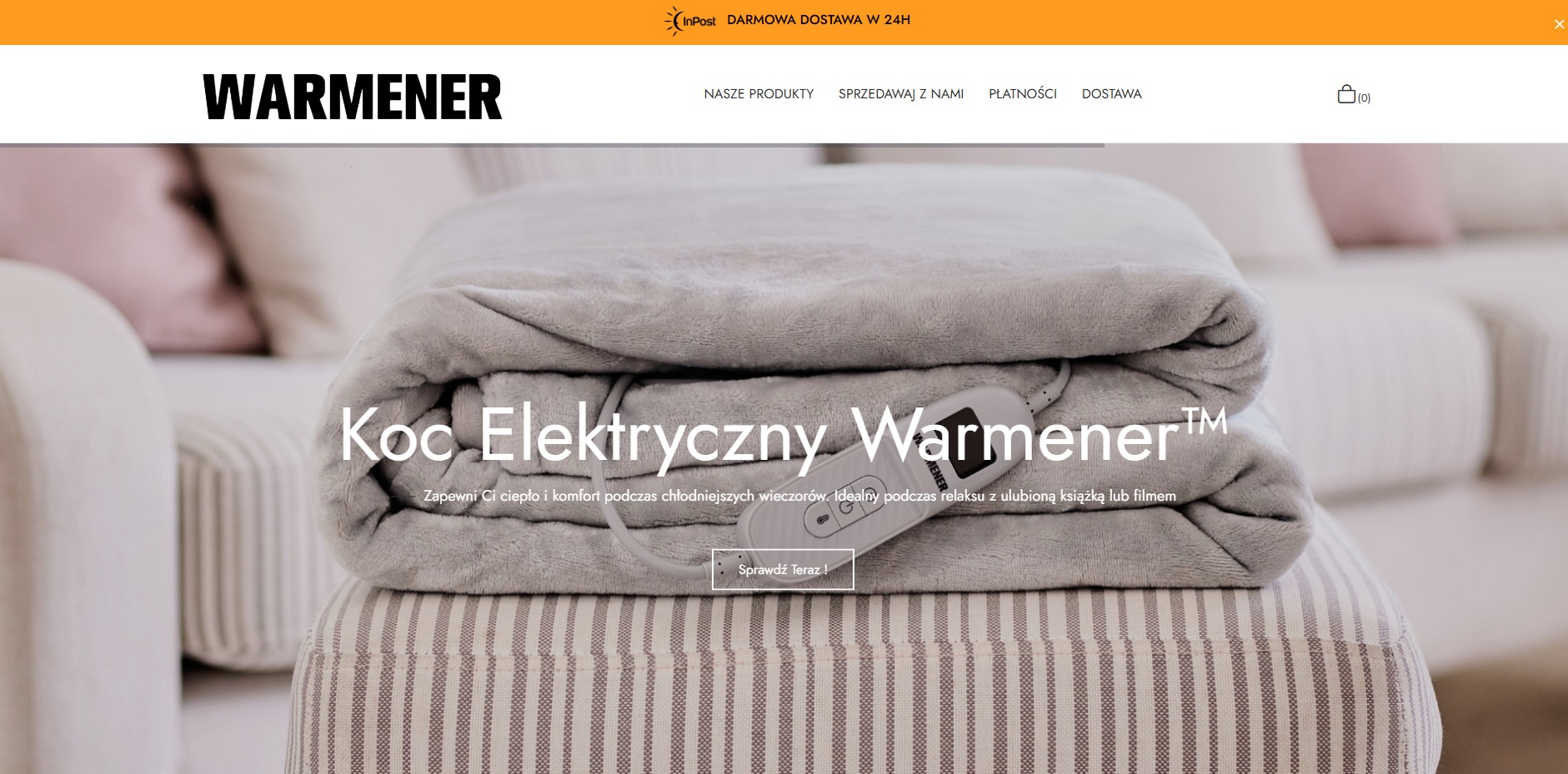 Szary koc elektryczny Warmener złożony na pufie w paski, z widocznym panelem sterowania i przewodami, na tle jasnej sofy.