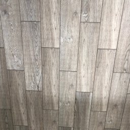 Filip W - Ułożona pod kątem podłoga z paneli imitujących jasne, szare drewno z widocznym wzorem słojów.