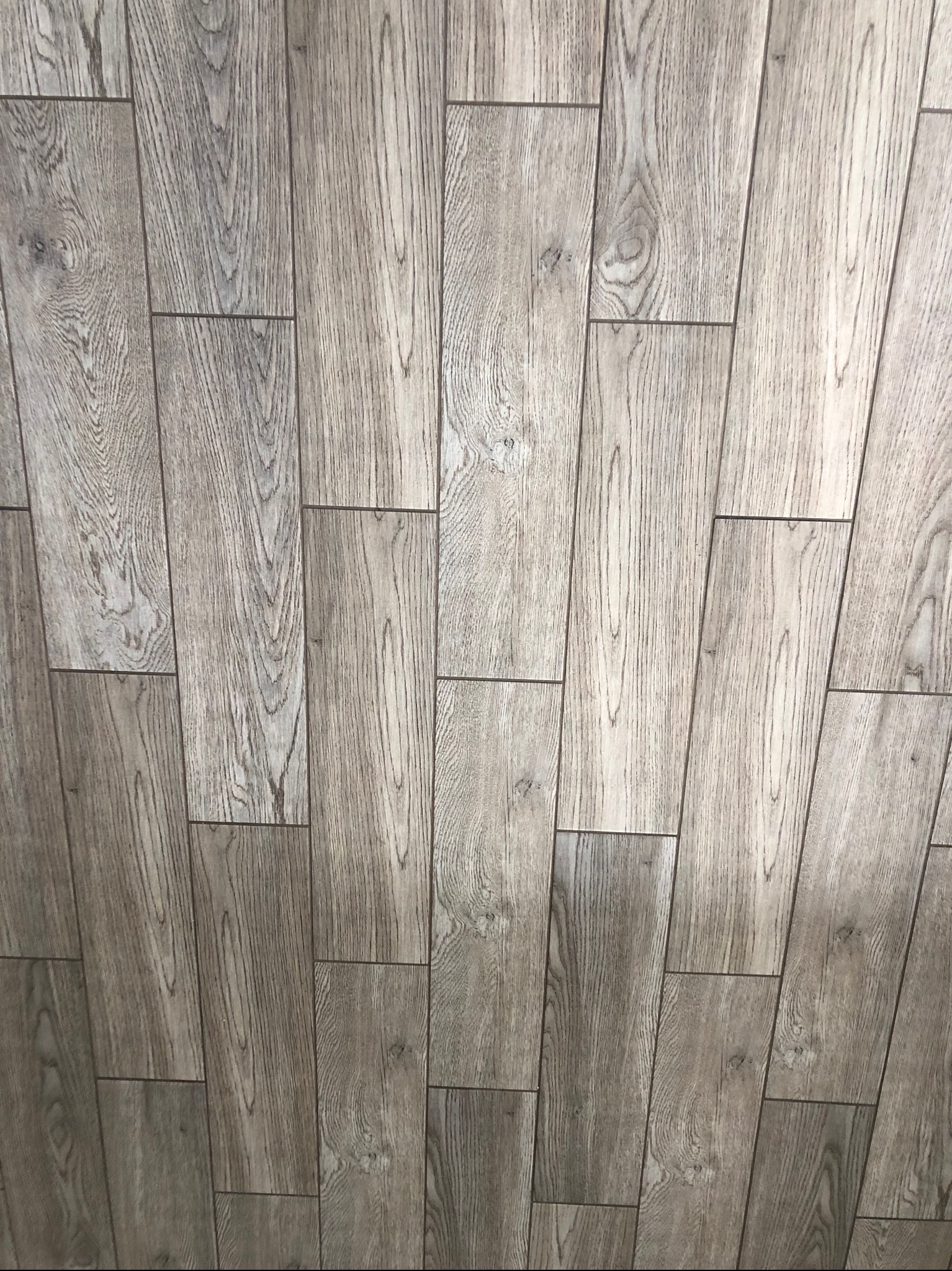 Ułożona pod kątem podłoga z paneli imitujących jasne, szare drewno z widocznym wzorem słojów.