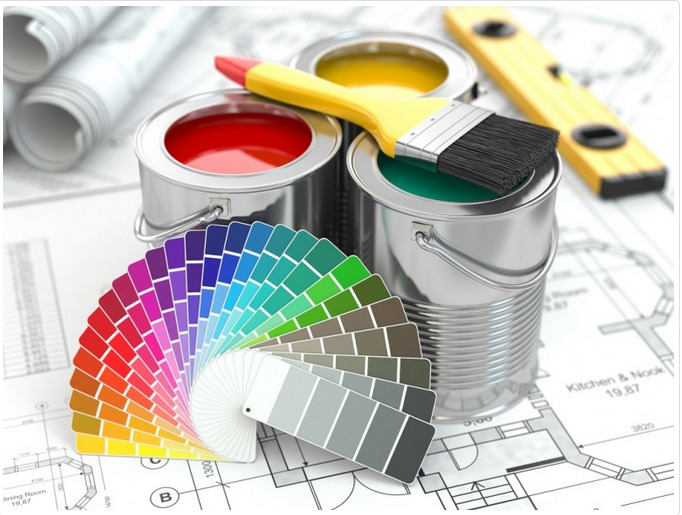 Puszki z farbami w kolorach czerwonym, żółtym i zielonym, pędzel z żółtą rączką, wachlarz kolorów i poziomica na tle planu architektonicznego.