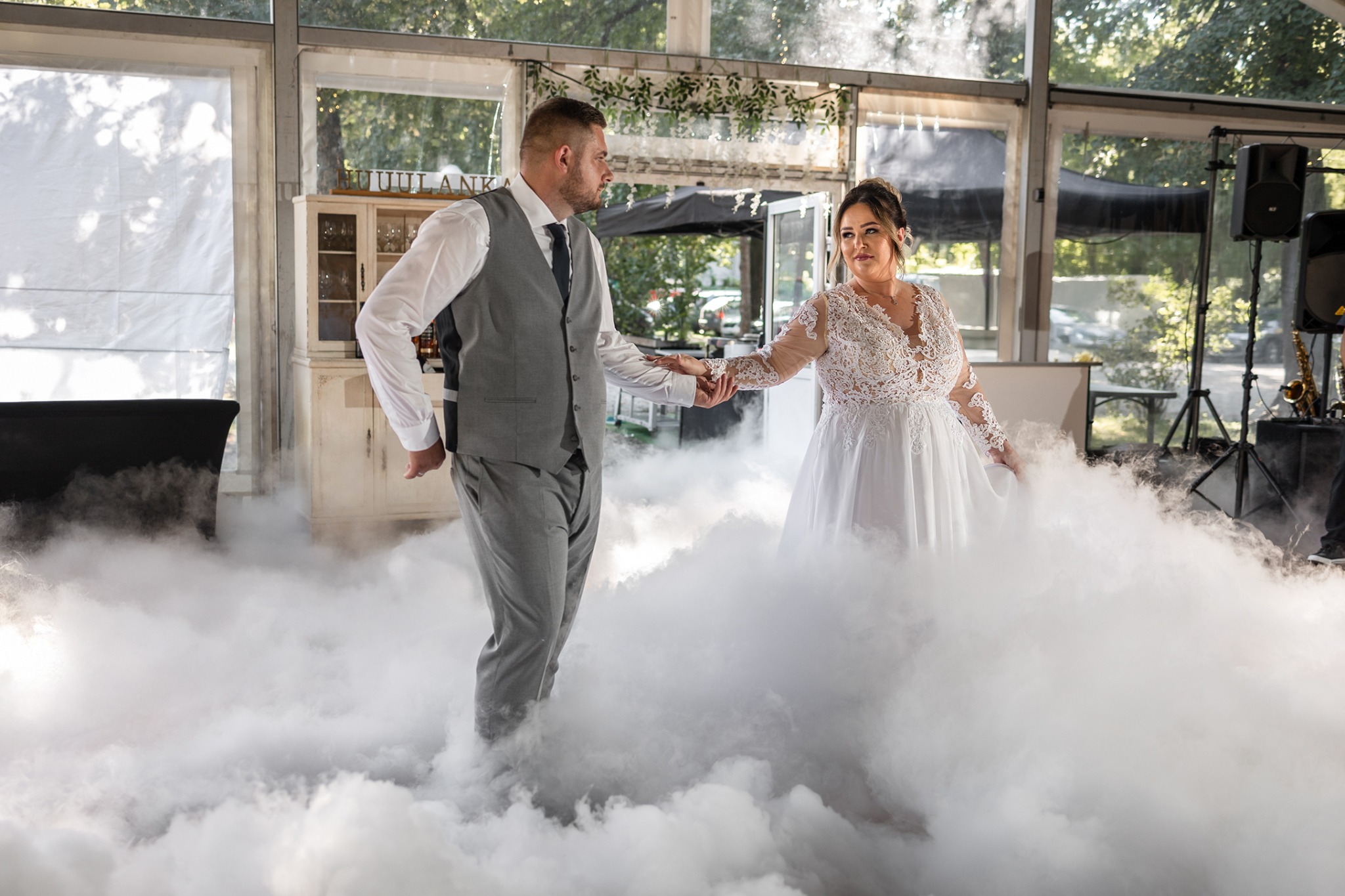 Para młoda w tańcu, otoczona sztuczną mgłą na sali weselnej z saksofonem w tle.