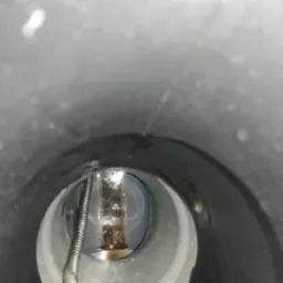 Wnętrze rury kanalizacyjnej w Parysowie, widok z góry na zatkany odpływ i sprężynę do udrażniania.