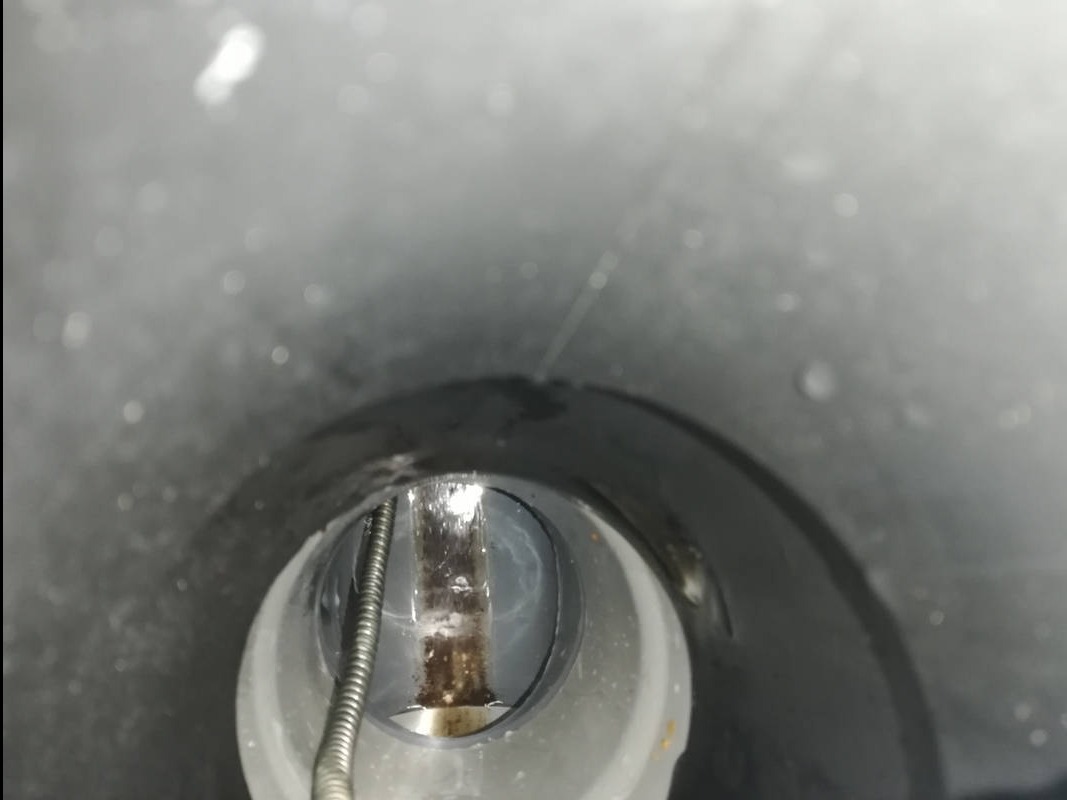 Wnętrze rury kanalizacyjnej w Parysowie, widok z góry na zatkany odpływ i sprężynę do udrażniania.