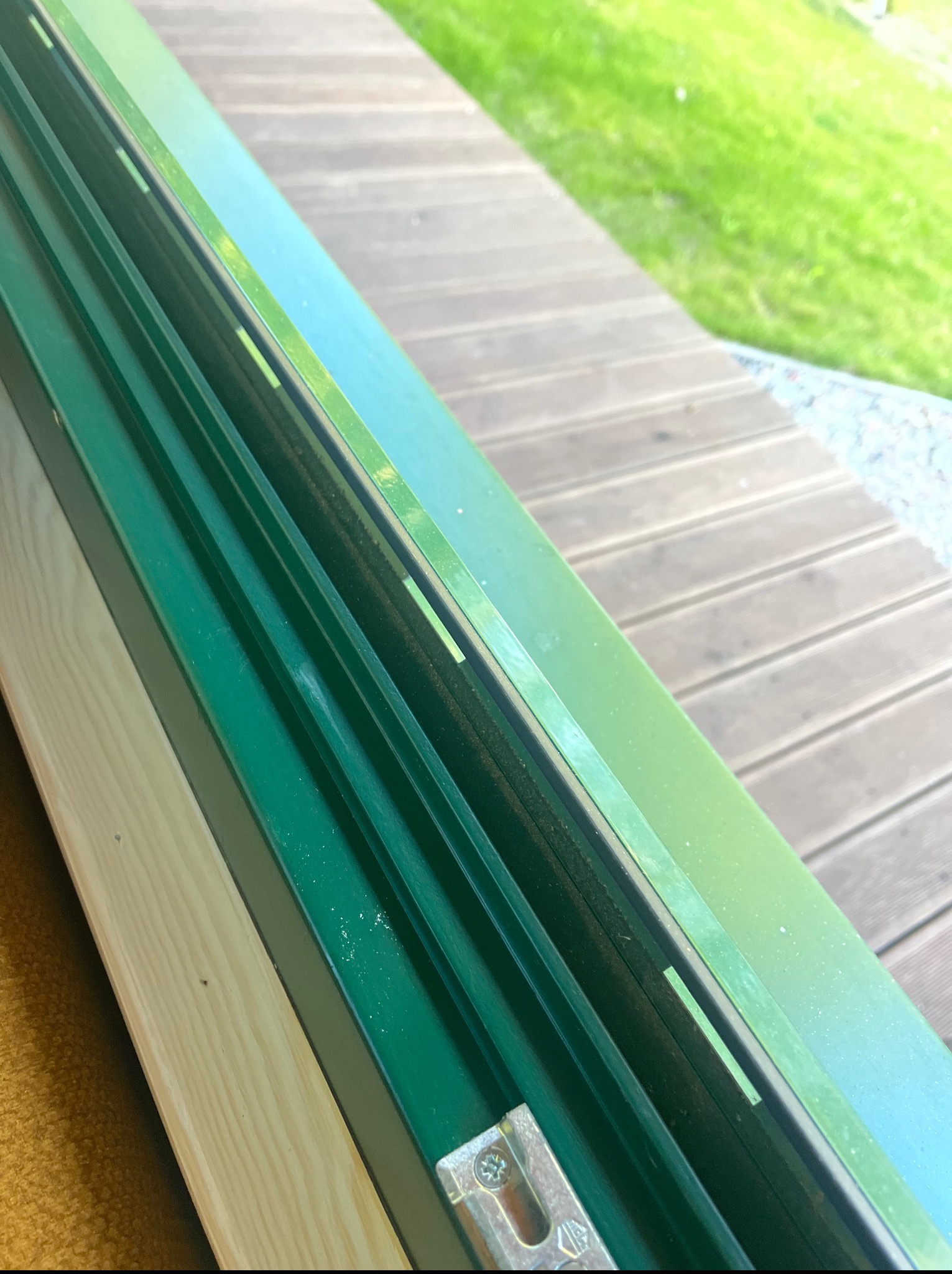 Zielony, czysty profil okienny po umyciu, widoczne drewniane elementy i fragment tarasu. Oświetlenie naturalne, słoneczny dzień.