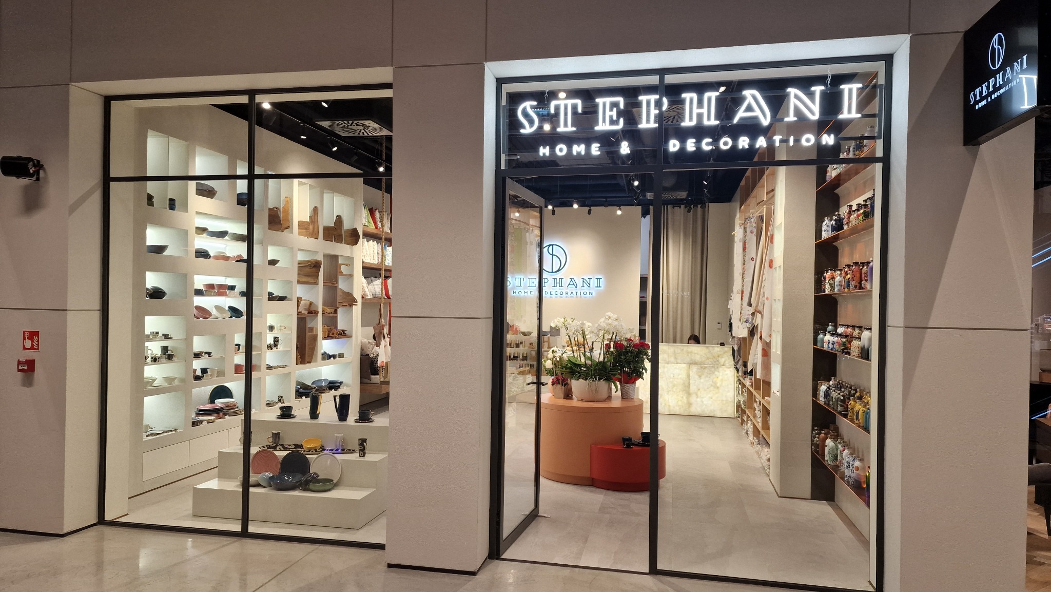 Eleganckie wejście do sklepu Stephani Home & Decoration z ekspozycją ceramiki i dekoracji wnętrz za szklaną witryną.