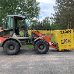 SGE GRZEGORZ GIL - Pomarańczowy ładowacz teleskopowy Atlas przewozi paletę żółtych bloczków Ytong na terenie budowy.