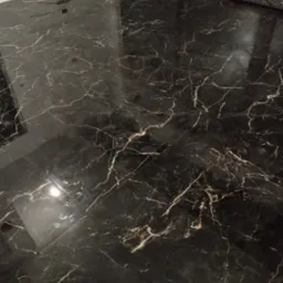 Błyszcząca, czarna marmurowa podłoga z białymi żyłami w trakcie układania w Łodzi, widoczne przewody elektryczne w ścianie.