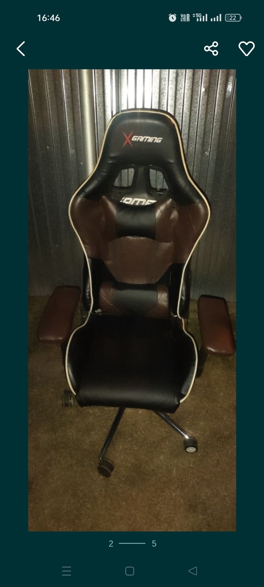 Czarne i brązowe krzesło gamingowe z logo X Gaming na tle metalowej ściany, widoczne ślady użytkowania.