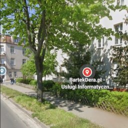 BartekDera.pl - Usługi Informatyczne i Edukacja mgr inż. Bartłomiej Dera - Budynek firmy informatycznej z widocznym adresem BartekDera.pl, otoczony zielenią, sfotografowany z poziomu ulicy.