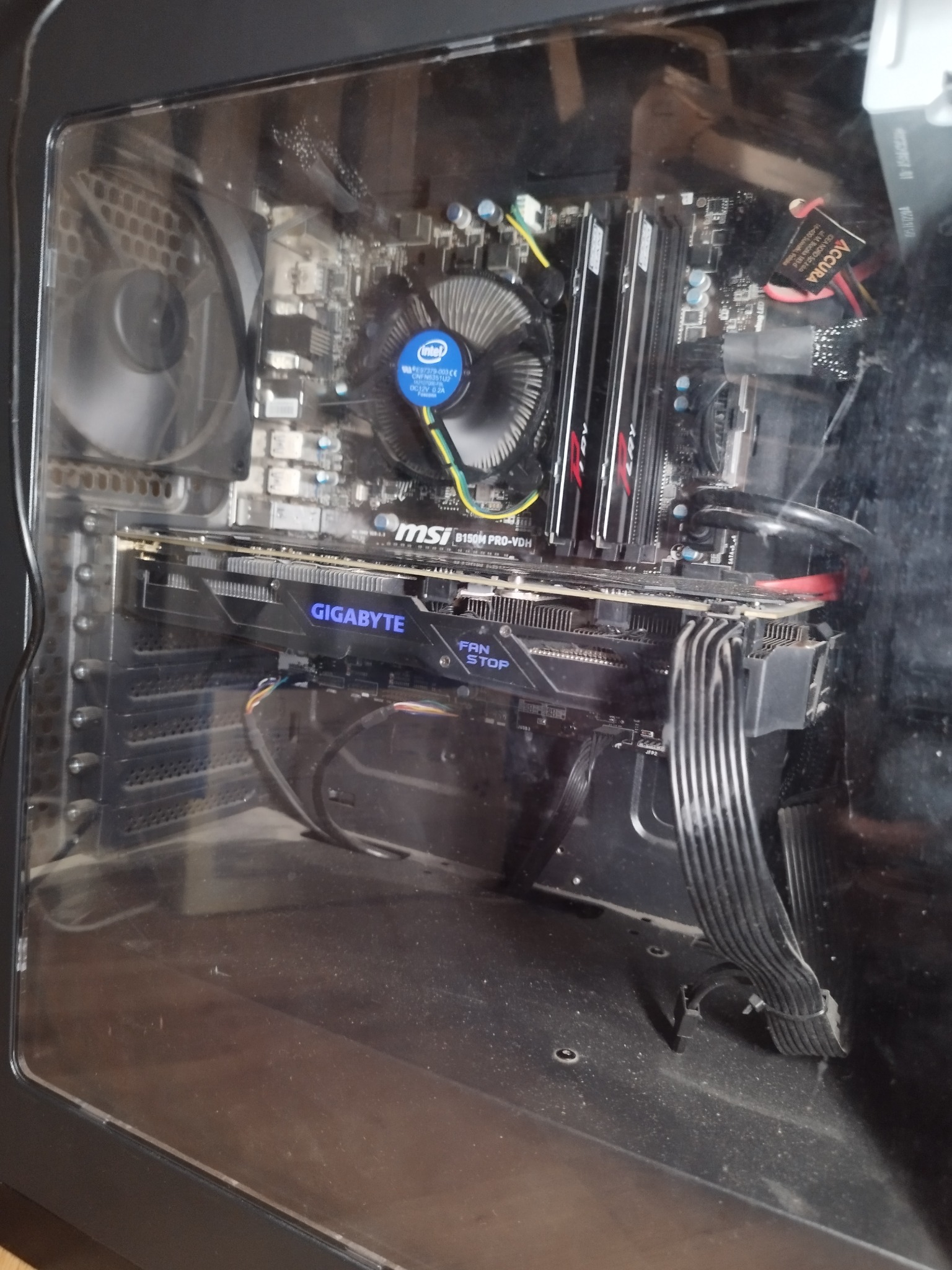 Wnętrze brudnej obudowy komputera stacjonarnego z widoczną płytą główną MSI B150M PRO-VDH, kartą graficzną Gigabyte z napisem 'FAN STOP' i chłodzeniem Intel. Widoczne okablowanie i wentylatory.