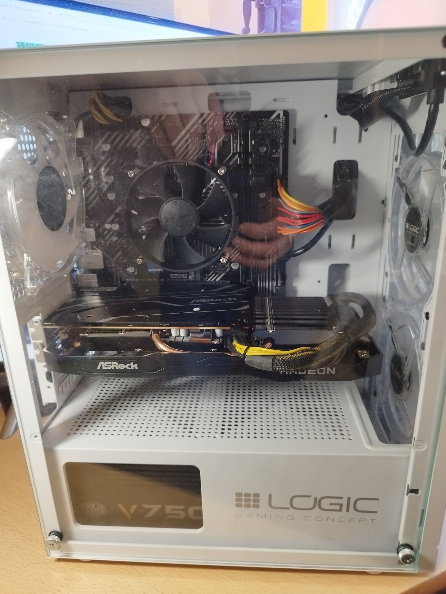 Wnętrze białej obudowy komputera stacjonarnego z widoczną kartą graficzną ASRock Radeon, płytą główną oraz zasilaczem Cooler Master V750, podświetlane wentylatory Logic Gaming Concept.