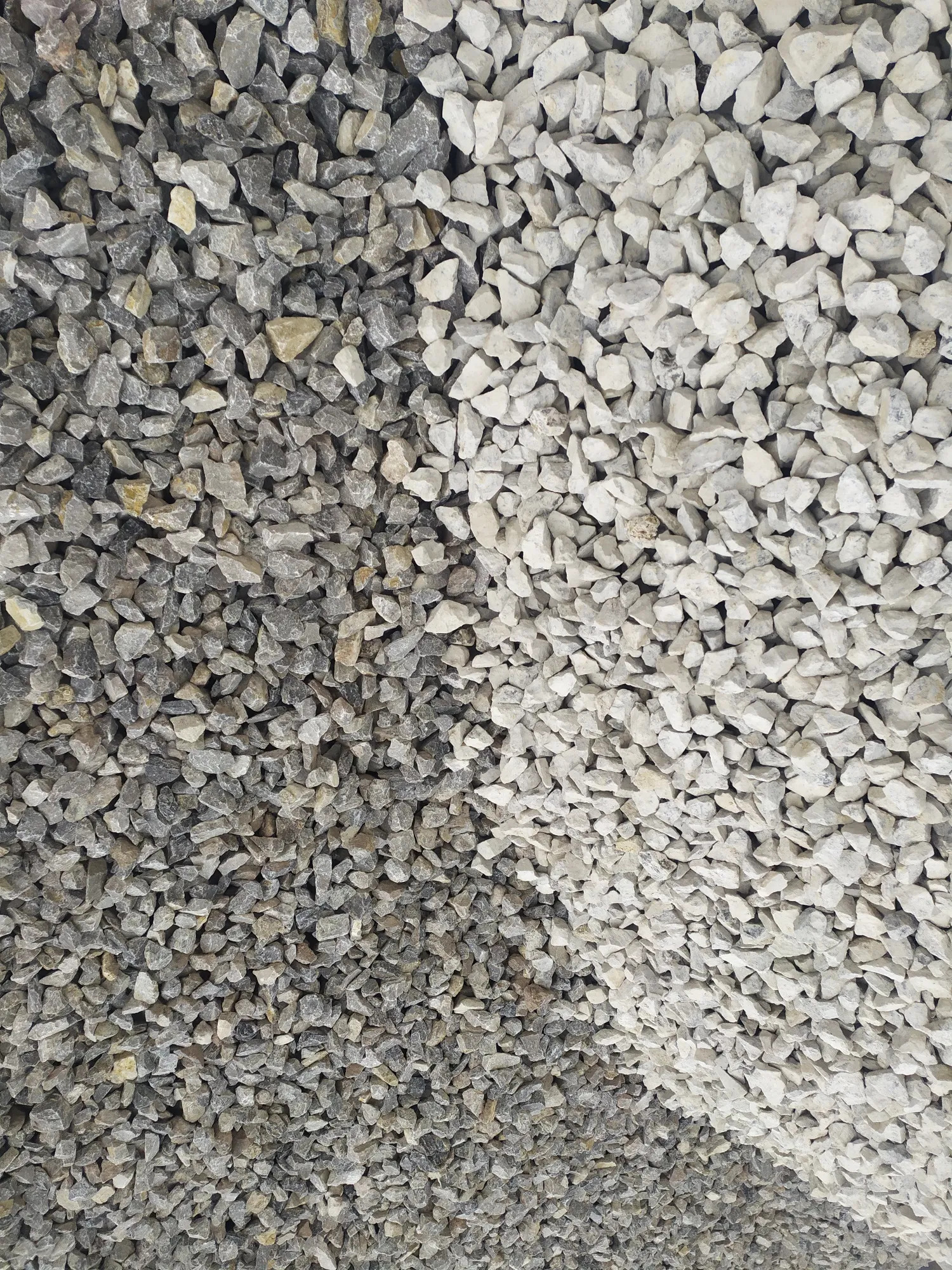 Dwie frakcje kruszywa: szare i białe, ułożone obok siebie, tworzące kontrast kolorystyczny. Drobne kamienie o ostrych krawędziach wypełniają całą powierzchnię kadru.