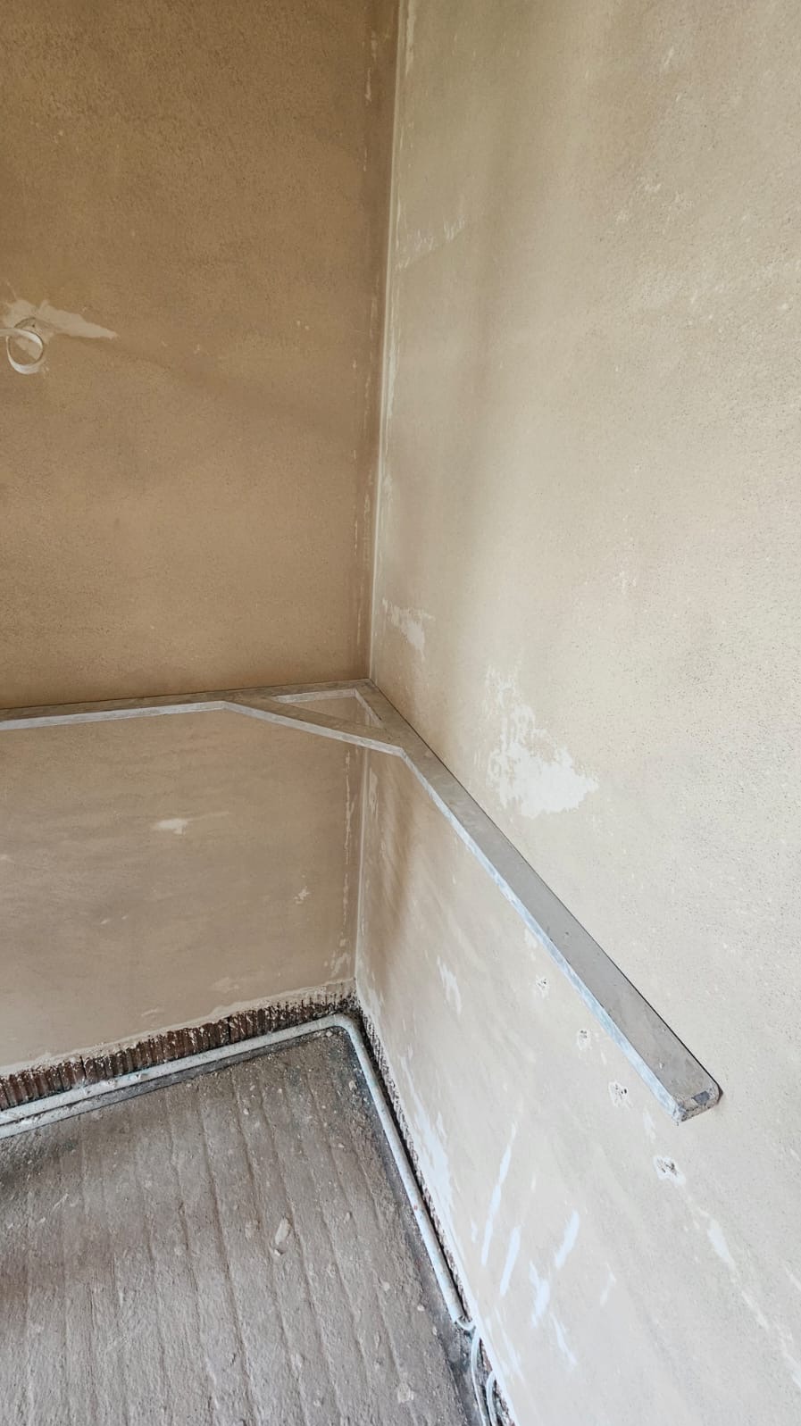 Przygotowanie do tynkowania maszynowego w Rosanowie: narożnik ściany z zamontowanymi profilami aluminiowymi, widoczne ślady zaprawy na ścianach i podłodze.