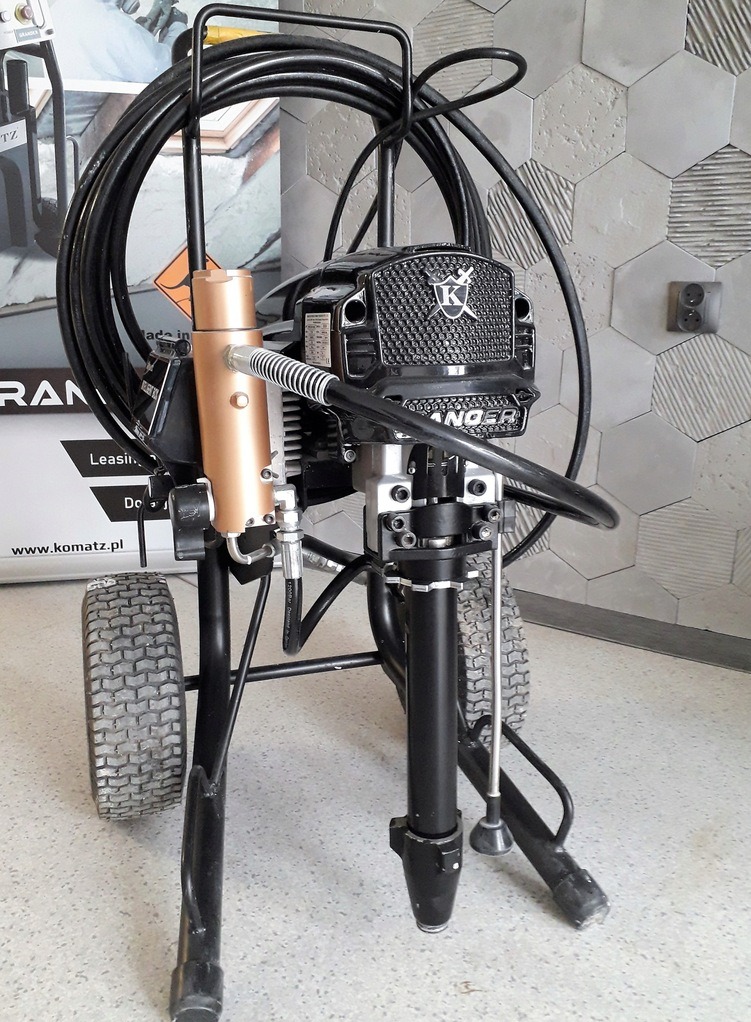 Profesjonalny agregat malarski Ranger na kółkach, z widocznym przewodem i lancą, stojący na posadzce, na tle ściany z szarych płytek o heksagonalnym wzorze.