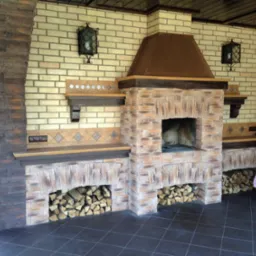 Zewnętrzny kominek z cegły i kamienia, z zapasem drewna pod spodem, oświetlony dekoracyjnymi lampami ściennymi.