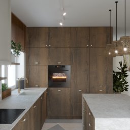 Aleksandra Brzozowicz KOMPOZYCJA STUDIO - Nowoczesna kuchnia z drewnianymi frontami, wyspą i sprzętem Siemens. Oświetlenie punktowe i lampy wiszące z abażurami. Rośliny doniczkowe dodają naturalnego akcentu.