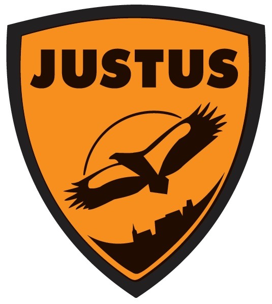 Pomarańczowo-czarne logo firmy Justus w kształcie tarczy z sylwetką lecącego orła na tle panoramy miasta.