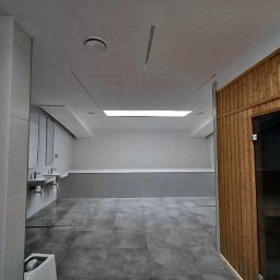 BudService Vasyl Kretsul - Nowoczesna łazienka publiczna z szarą podłogą, umywalkami i drewnianą sauną. Minimalistyczny design, oświetlenie sufitowe.