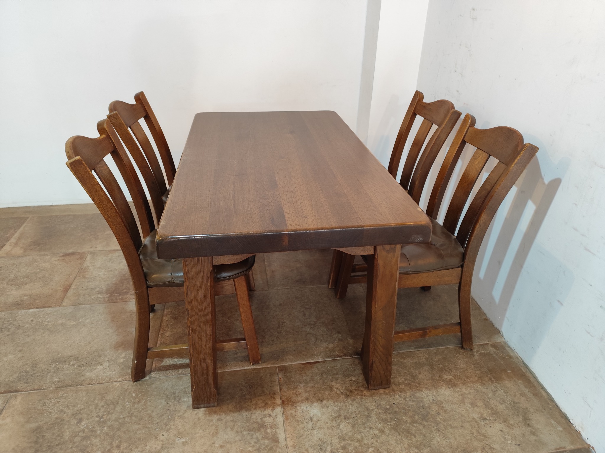 Drewniany stół z krzesłami w rustykalnym stylu w Nowej Bystrzycy, ustawiony na kamiennej podłodze przy białej ścianie.