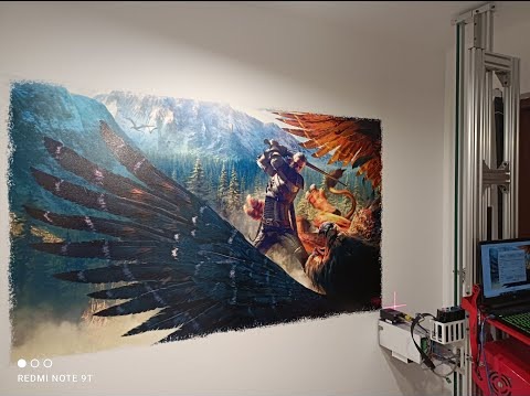 Drukarka ścienna drukuje na ścianie obraz z gry Wiedźmin, przedstawiający Geralta walczącego z gryfem na tle górskiego krajobrazu.