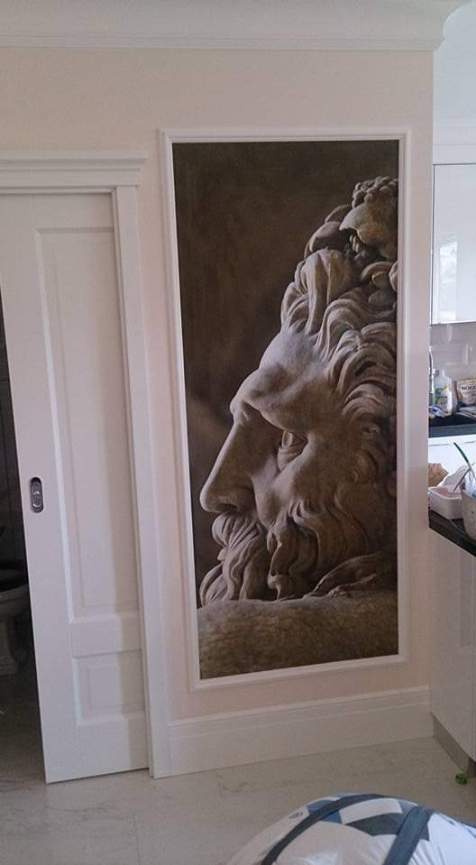 Wnętrze z fototapetą przedstawiającą popiersie rzeźby klasycznej w profilu, umieszczoną między przesuwnymi drzwiami a szafkami kuchennymi.