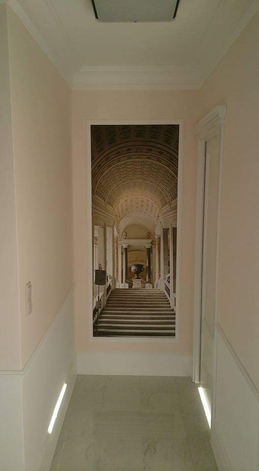 Korytarz z dekoracyjną fototapetą przedstawiającą schody w architekturze klasycznej, wykończony listwami przypodłogowymi i oświetleniem punktowym.