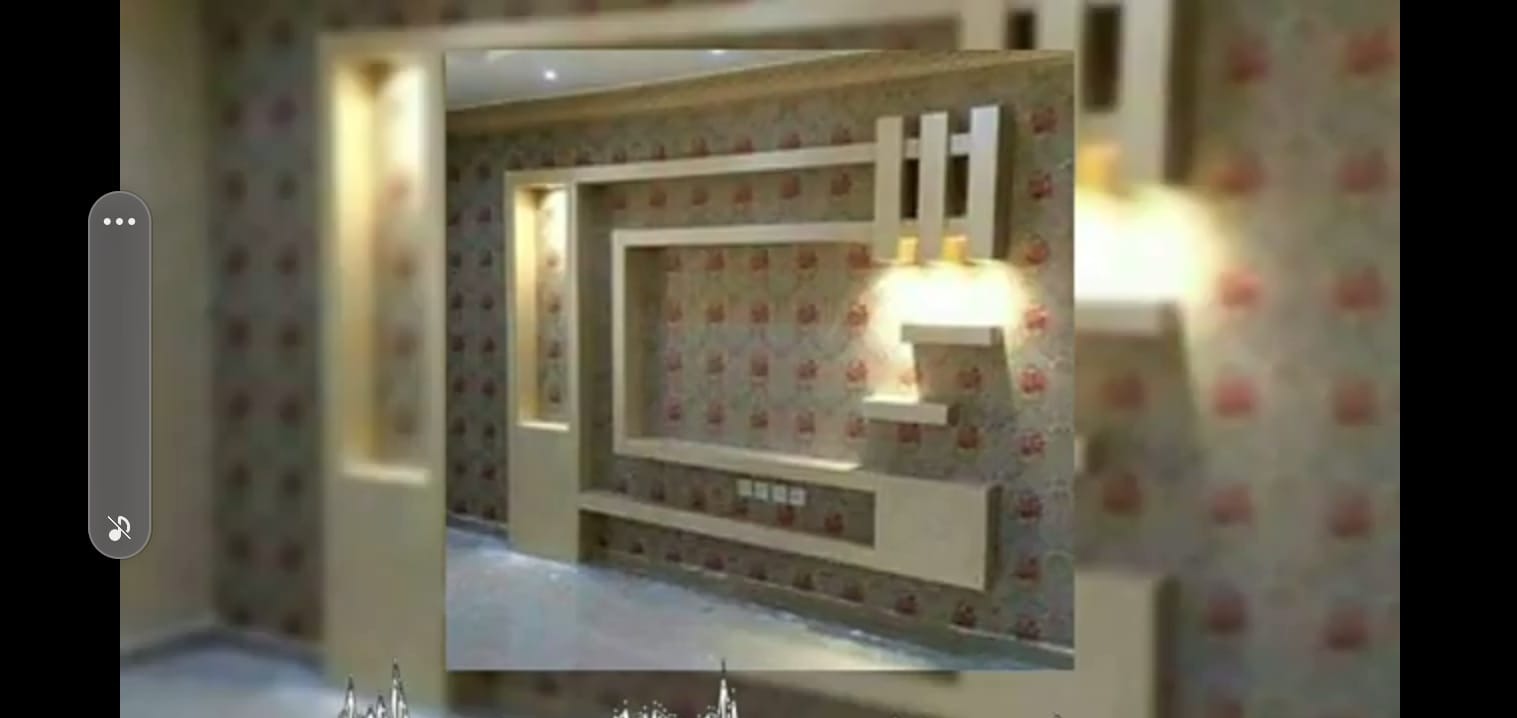 Beżowa zabudowa ściany z wnękami i dekoracyjnymi elementami oświetleniowymi na tle ściany w kwiecistej tapecie.