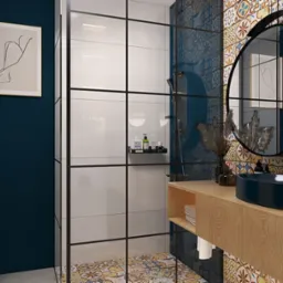 Niebieska łazienka z kabiną prysznicową typu walk-in, okrągłym lustrem z czarną ramą i drewnianą szafką z umywalką w kształcie łódki.