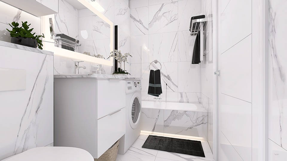 Biała łazienka z marmurowymi płytkami, pralką zabudowaną w szafce pod umywalką, oświetleniem LED i czarnymi akcentami w postaci ręczników i dywanika.