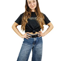 Daniel Smoter - Portret kobiety w czarnym t-shircie z logo 'FABROWS MORE ACADEMY' i szerokich dżinsach, ręce na biodrach, na białym tle.