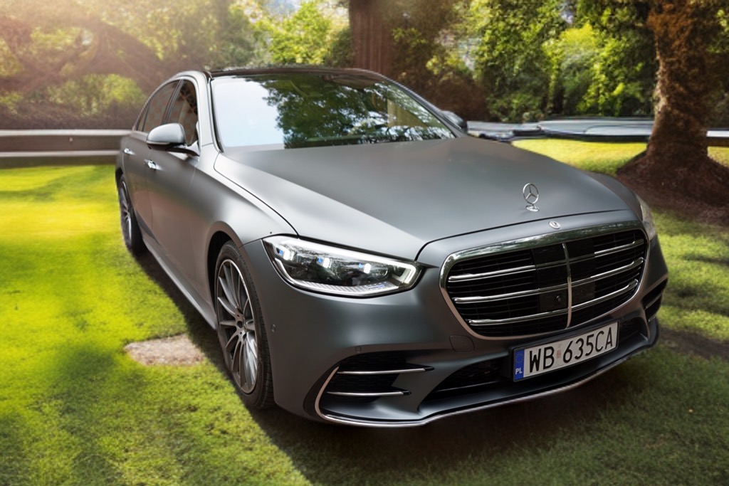 Matowy, szary Mercedes-Benz klasy S zaparkowany na trawie, z widoczną tablicą rejestracyjną i logo marki na masce.