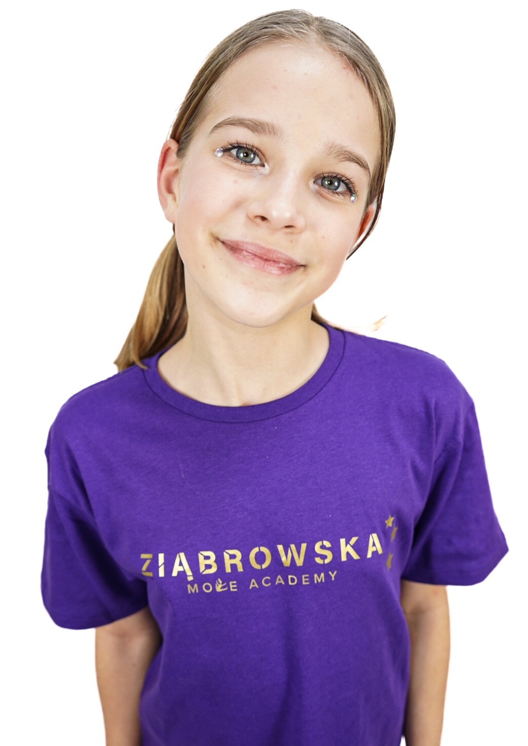 Portret uśmiechniętej nastolatki w fioletowej koszulce z złotym napisem 'ZIĄBROWSKA MOVE ACADEMY' i brokatowymi naklejkami pod oczami na białym tle.