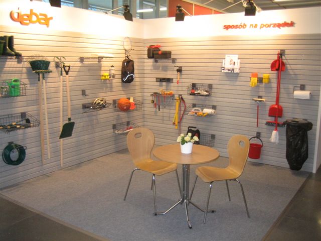 Ekspozycja systemu porządkowania przestrzeni garażowej lub pomieszczenia gospodarczego z panelami ściennymi, haczykami i koszami na narzędzia, akcesoria ogrodowe i sprzęt sportowy; na środku...