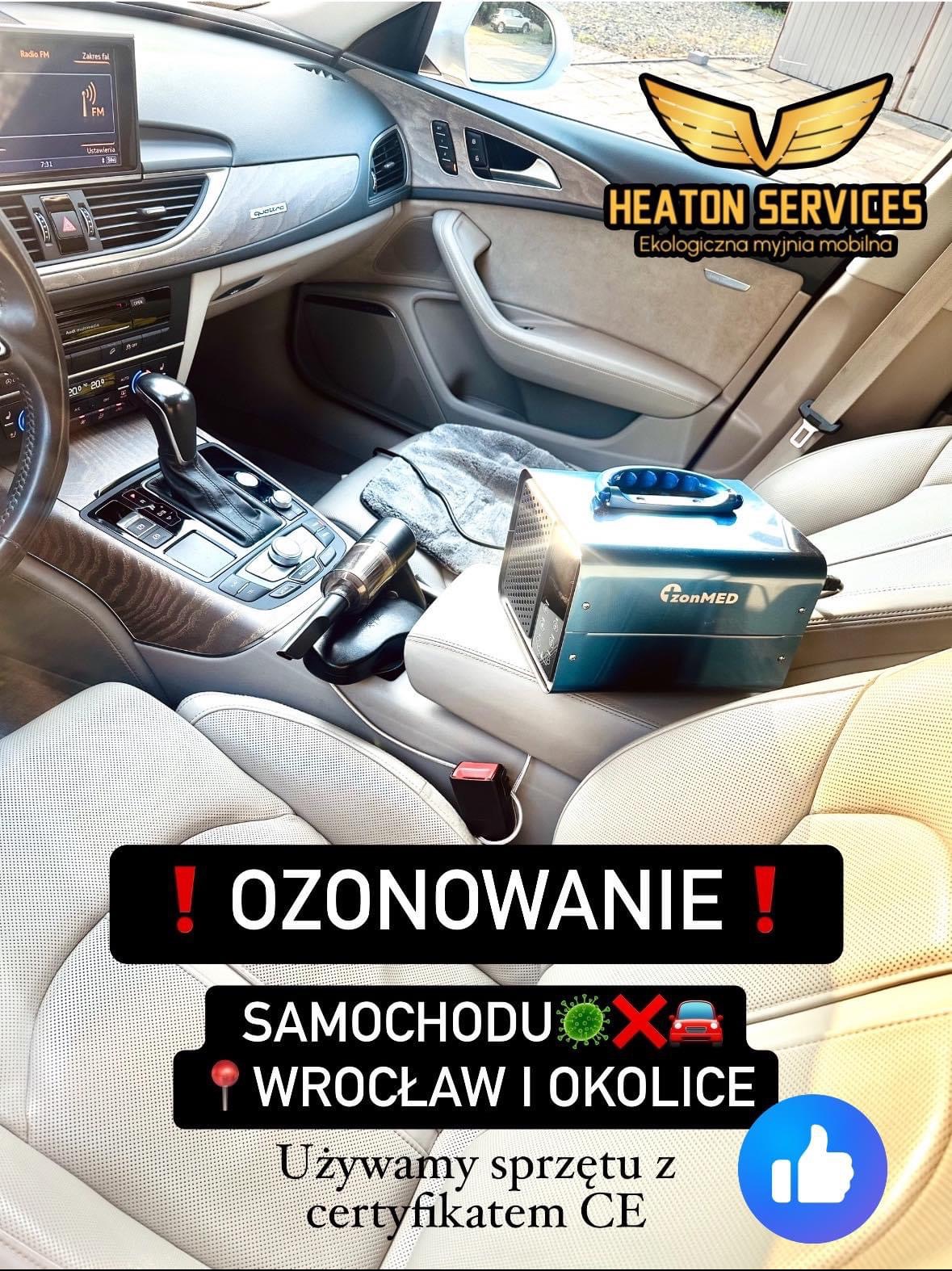 Wnętrze samochodu z ozonowaniem, widoczny generator ozonu ZonMED na siedzeniu pasażera i odkurzacz ręczny na konsoli środkowej, deska rozdzielcza Audi, napis 'OZONOWANIE SAMOCHODU WROCŁAW I OKOLICE'.