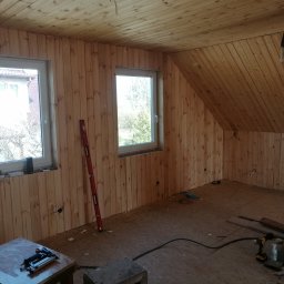 BCV SERWIS - MICHAŁ MAŁOLEPSZY - Wnętrze w trakcie wykańczania boazerią drewnianą; widoczne narzędzia, poziomica, okna z widokiem na zewnątrz oraz fragment komina z cegły. Prace wykończeniowe w domku kanadyjskim.