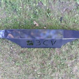 BCV SERWIS - MICHAŁ MAŁOLEPSZY - Czarny, metalowy element z wyciętym napisem '3CV' leżący na trawie.