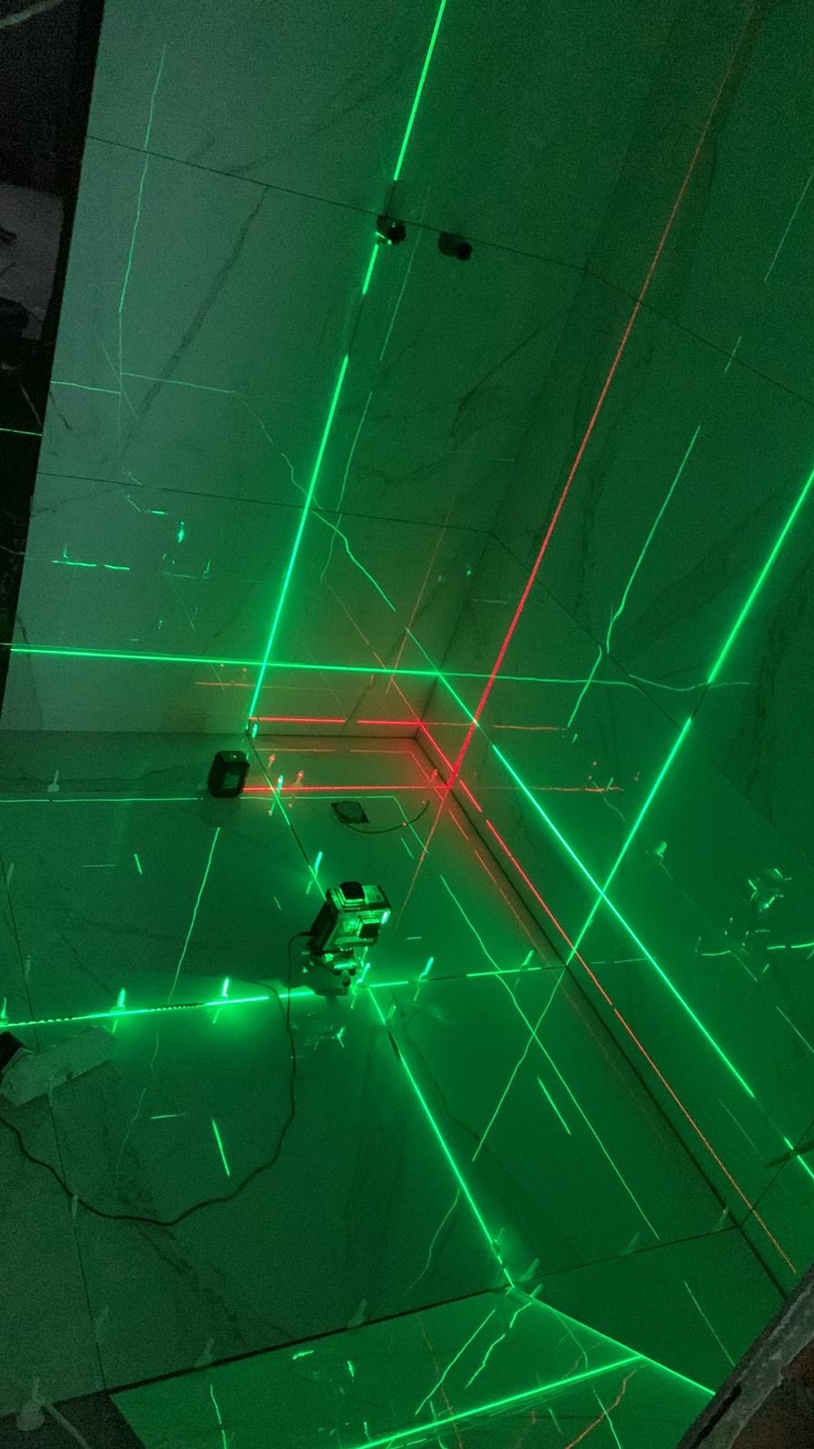 Ustawianie poziomu płytek w łazience za pomocą lasera krzyżowego emitującego zielone i czerwone linie.