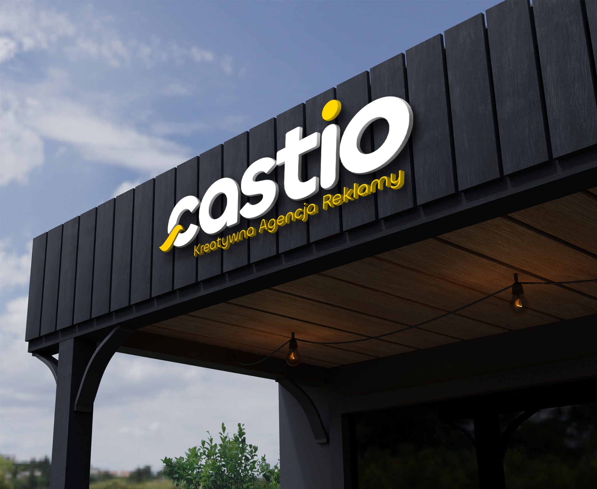 Elewacja budynku z podświetlanym, trójwymiarowym logo 'castio' i napisem 'Kreatywna Agencja Reklamy' w kolorze żółtym, na tle błękitnego nieba.
