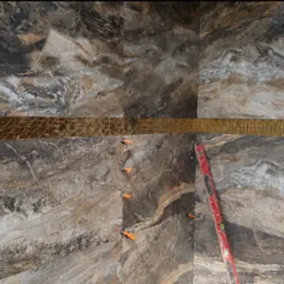 Montaż płytek imitujących marmur z dekoracyjną, złotą listwą, poziomica przy ścianie, widoczne klipsy poziomujące.