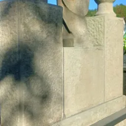 Fragment pomnika nagrobnego z trzema rzeźbami z jasnego kamienia na tle błękitnego nieba, widoczne detale obróbki kamienia i cieniowanie