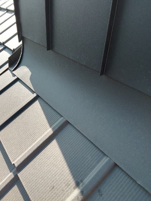 Szczegółowe ujęcie połączenia obróbki blacharskiej z panelami dachowymi w kolorze grafitowym, widoczne cieniowanie i faktura materiałów.